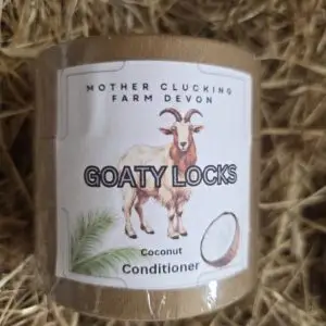 Bottle of 'Goaty Locks' Coconut Conditioner from Mother Clucking Farm Devon, with a goat illustration on a straw background.
